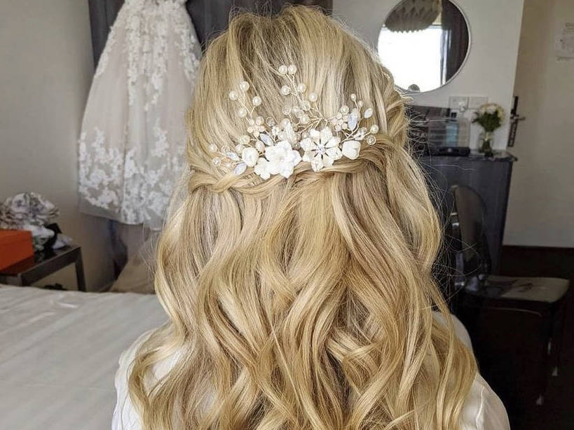 An image of a brides hair taken from behind showing flowing locks and a white bridal accessory